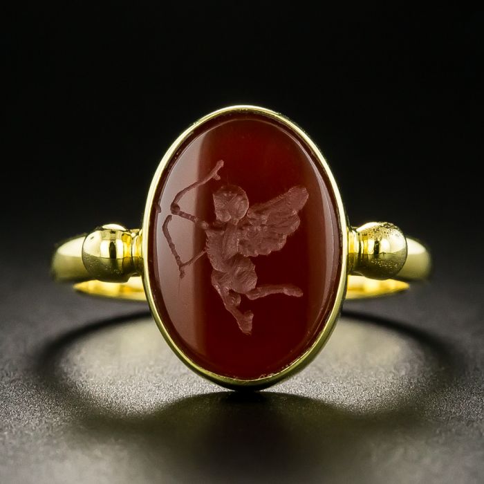 Ring with a carved carnelian ring, Gold ring. Consisting of a wide, flat  band with soldered gold wire. In a tall cupboard in the shape of a flower  calyx, a carnelian intag -